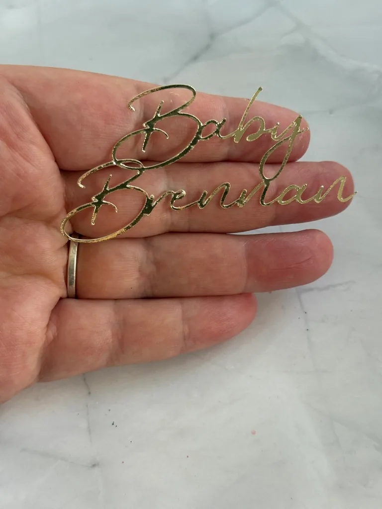 Gold mirror Baby Brennan script plaque held in a hand