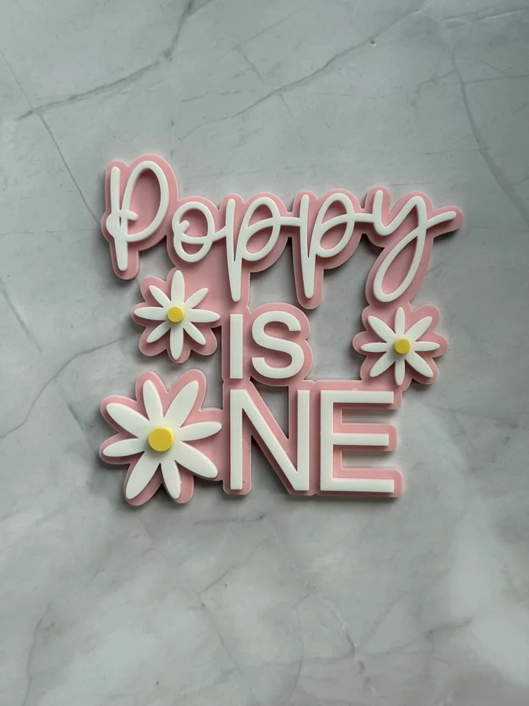 Pink and white layered Poppy is One topper with daisies
