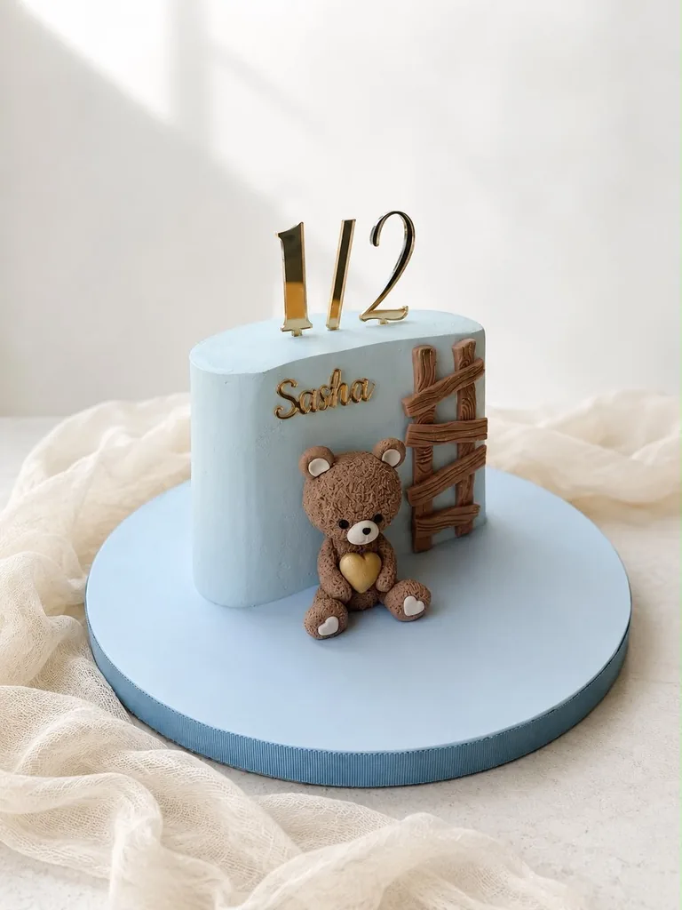 Pale blue half birthday cake with gold one half numerals and the name Sasha